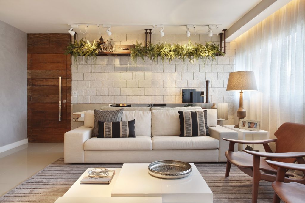 sala com porta de madeira, decoração com lâmpadas em cima do sofa , abajur e cadeira como decoração 