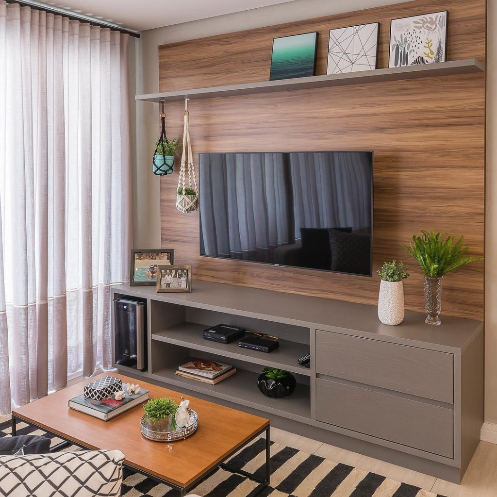 sala simples, com decoração leve com alguns vasos de planta no rack e mesinha de centro 