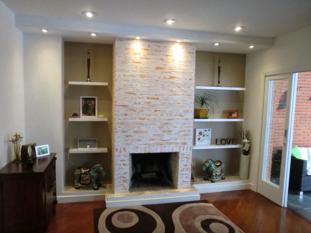 sala de estar pequena com lareira central e objetos de decoração na estante ao lado 
