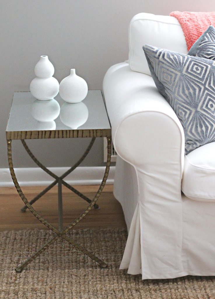 mesa quadrada de vidro e madeira, com dois vasos em cima brancos para decoração de uma sala 