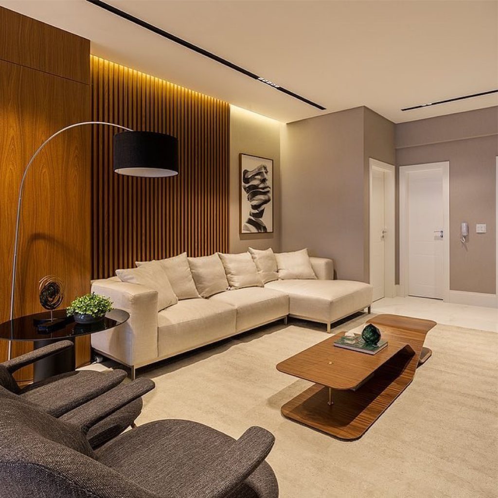 sala grande com parede estilo madeiras, sofa grande L na cor clara , mesa de canto ao lado sdo sofa 