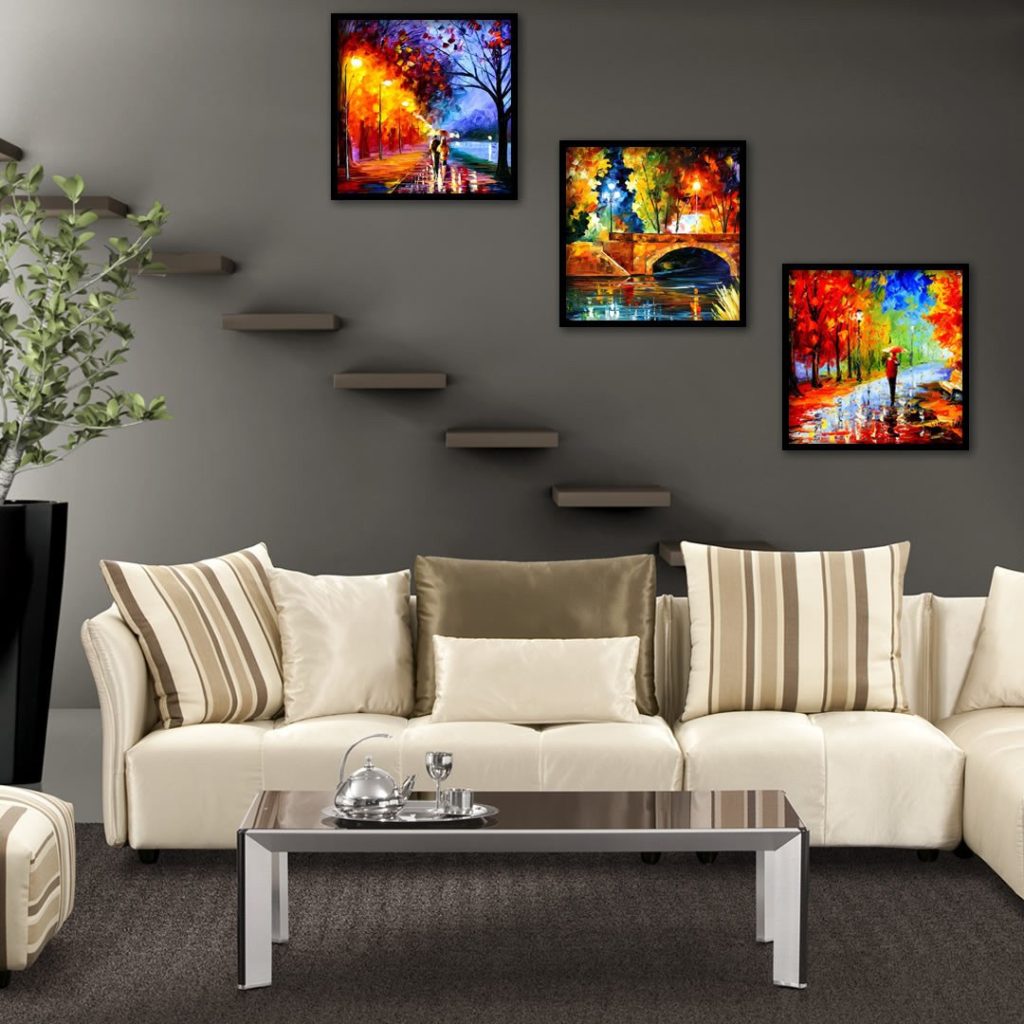 sala com parede pendurada trio de quadros coloridos , sofa em L, um vaso de planta ao lado do sofa 