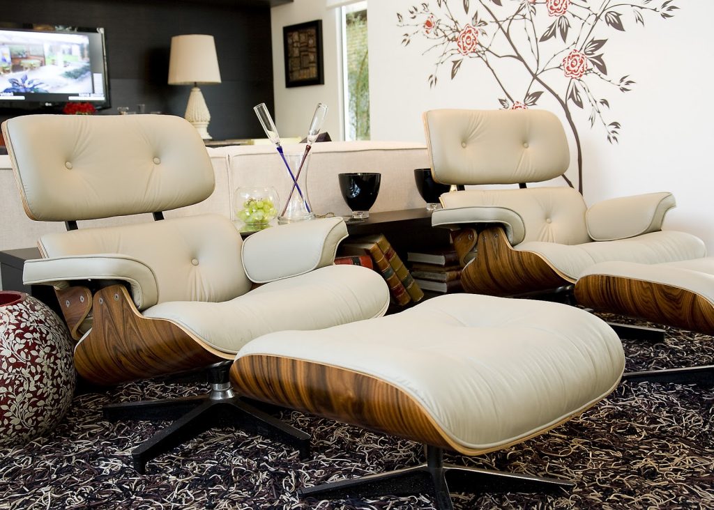 2 poltronas estilos eames nas cores bege e amadeirado na sala.