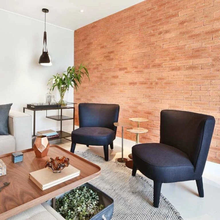 sala de estar com 2 poltronas pretas, luz natural e parede estilo amadeirado 