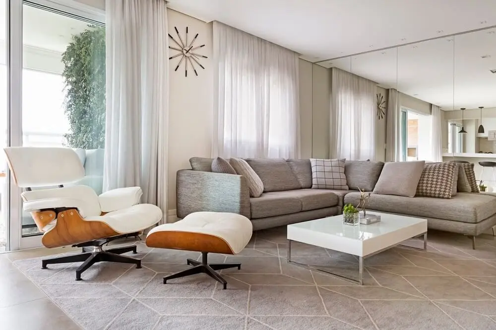 Sala ampla com decorações claras e uma poltrona versátil ao lado do sofa grande 