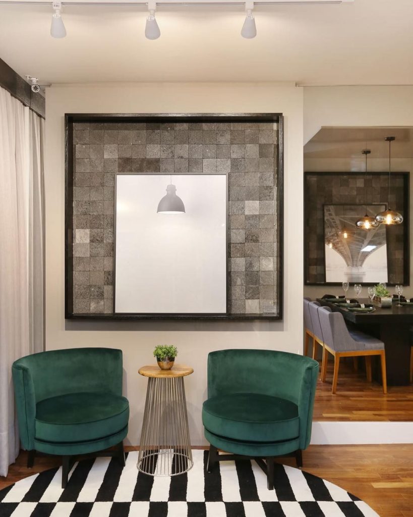 ambiente com 2 poltronas na cor verde e um quadro grande atras 