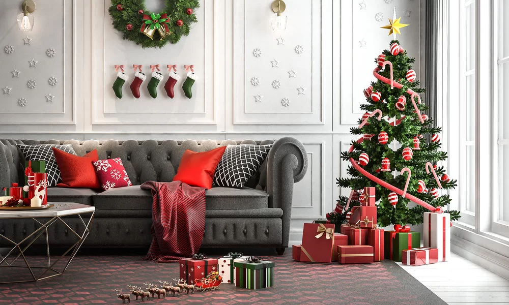 sala com sofa grande na cor cinca e arvore de natal com presentes para decoração