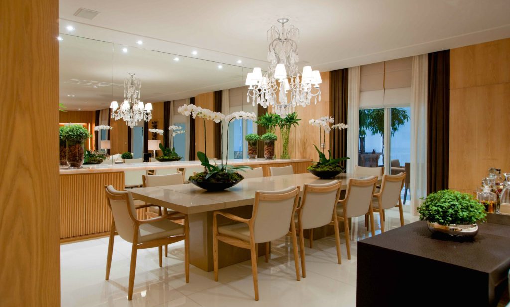 sala de jantar com lustre central, mesa sofisticada com decoração em bege e amadeirado