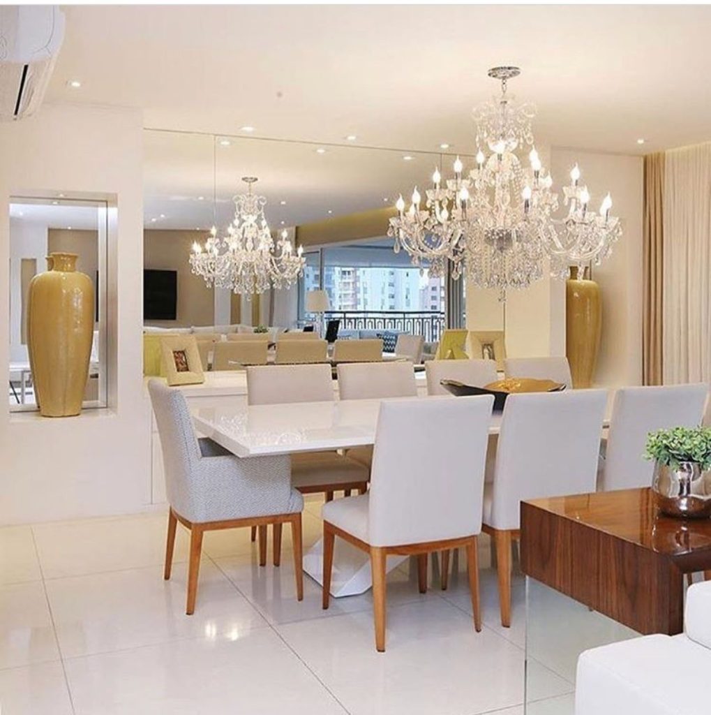 sala de jantar com lustre moderno pendurado no centro de uma mesa de jantar com 8 lugares