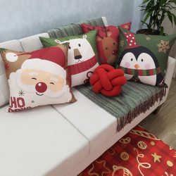 sala de estar com sofá branco com uma manta esverdeada e almofadas temática de natal para decorar, ao lado um vaso grande com plantas.