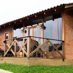 casa de madeira com varanda toda feita de madeira com vidros grandes na porta e janelas.