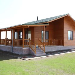 Casa de madeira com varanda ampla, nas laterais jardim e calçadas.