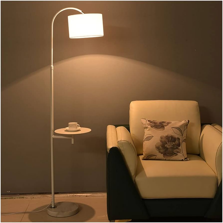 ambiente com uma poltrona na cor bege e preto com almofada em cima estampada de flores, ao lado uma luminária de chão alta.