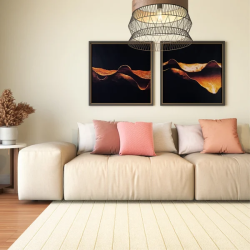 sala de estar com dois lugares grandes com almofadas nas cores branco e rosa bebe, na parede atrás do sofa dois quadros grandes pendurados decorativos, ao lado uma mesinha com vaso de planta.