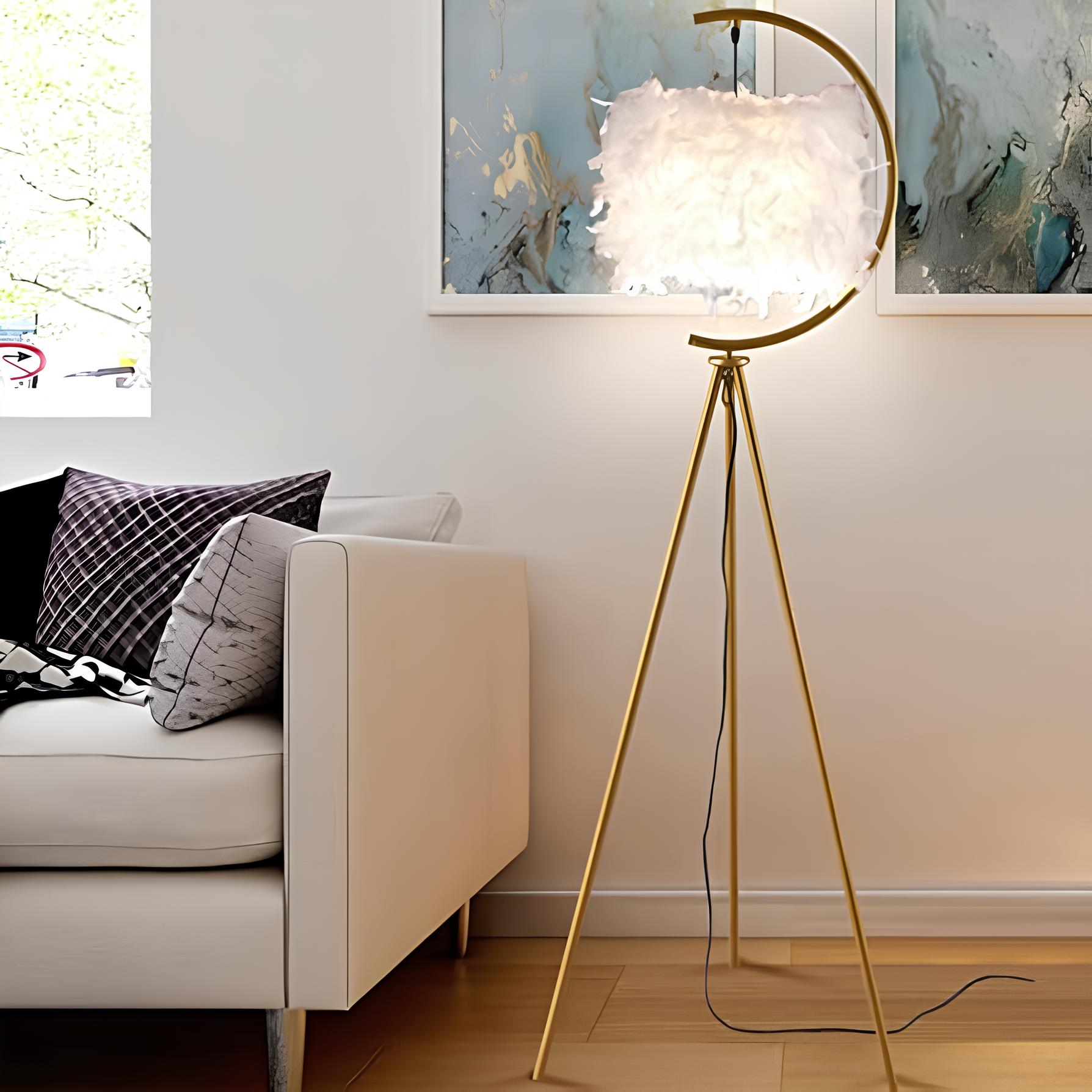sala com um sofá branco com almofadas em cima dele, ao lado uma luminária alta, ao fundo na parede quadros decorativos pendurados.