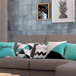 sala de estar com sofá em L na cor cinza com almofadas em cima dela decorando, atrás do sofá na parede quadros decorativos pendurados.