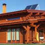 Casa de madeira ampla e moderna de andar, com garagem, varanda e sacada, portas e janelas de vidros, em volta dela gramado.